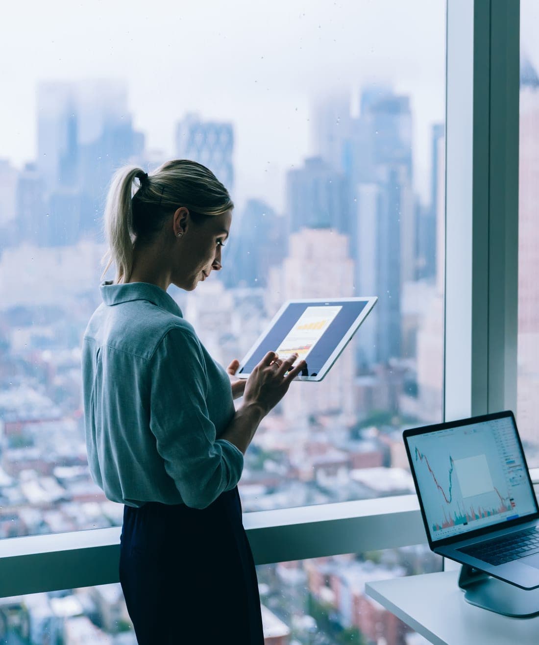 A professional reviewing work on a tablet in a high-rise office
