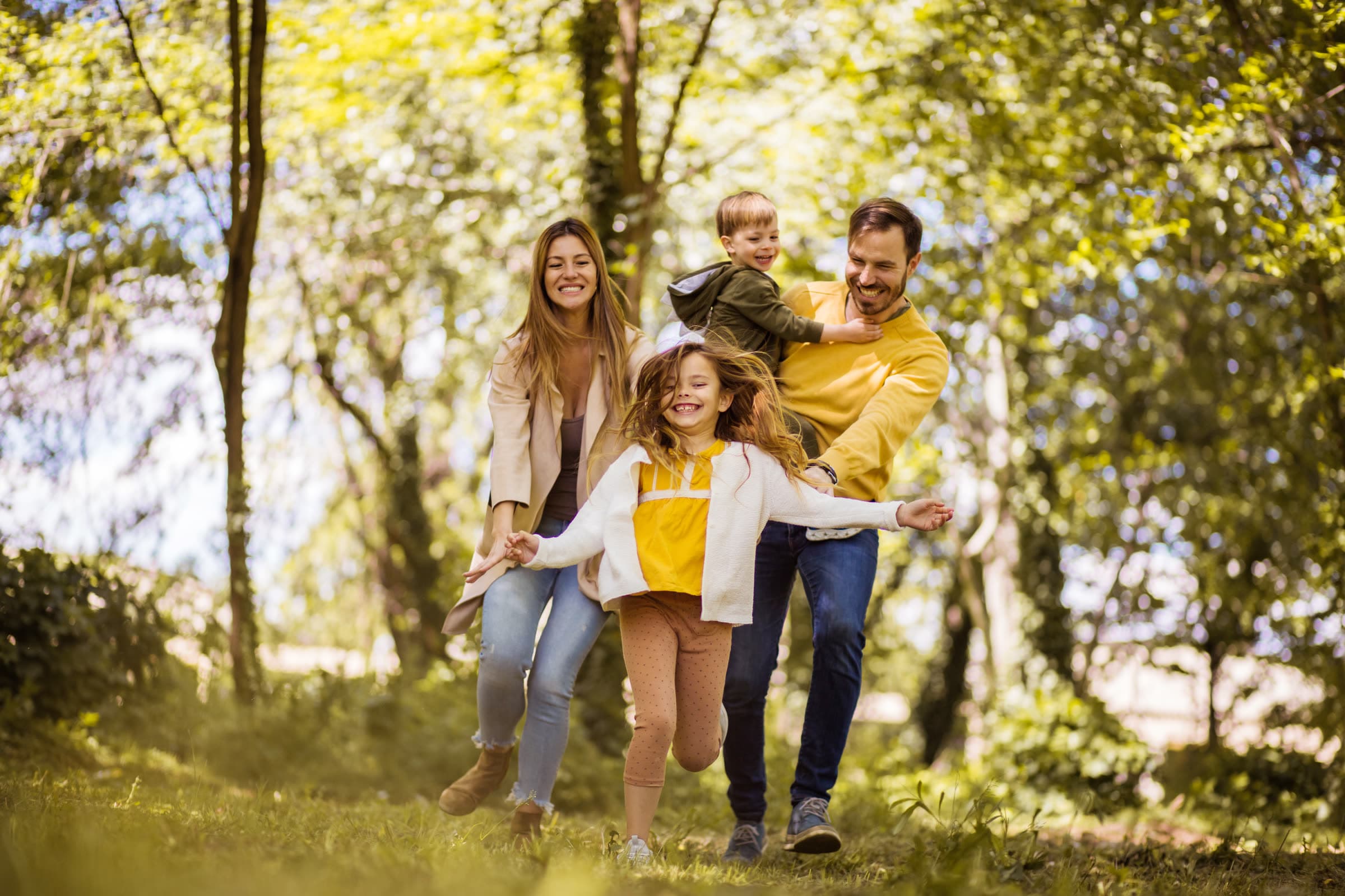 Parents and two children playing together outdoors on a sunny day